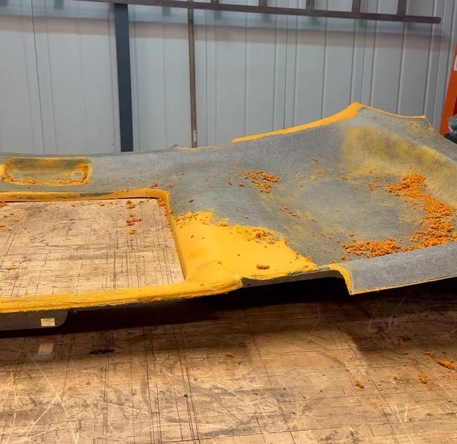 Coque de ciel de toit d’Audi A1 posée sur l’établi, couverte de miettes de mousse orange, avec la découpe du toit ouvrant
