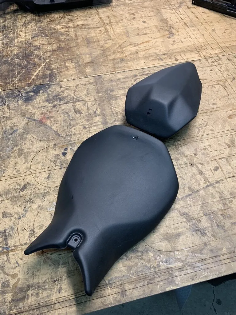 Selle de moto et son dosseret passager refaits, posés côte à côte sur l’établi