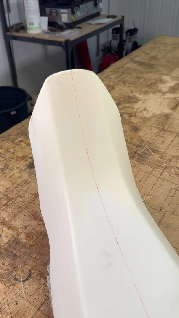 Mousse de selle de moto brute, avant découpe et galbe, posée sur l’établi